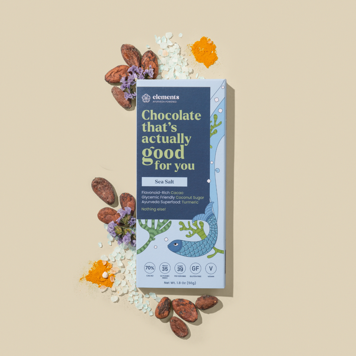 A bar of chocolate from elements wellness, specifically 'Chocolate that's actually good for you' in Sea Salt flavor, presented on a beige background with decorative cacao nibs, purple flowers, and orange powder.