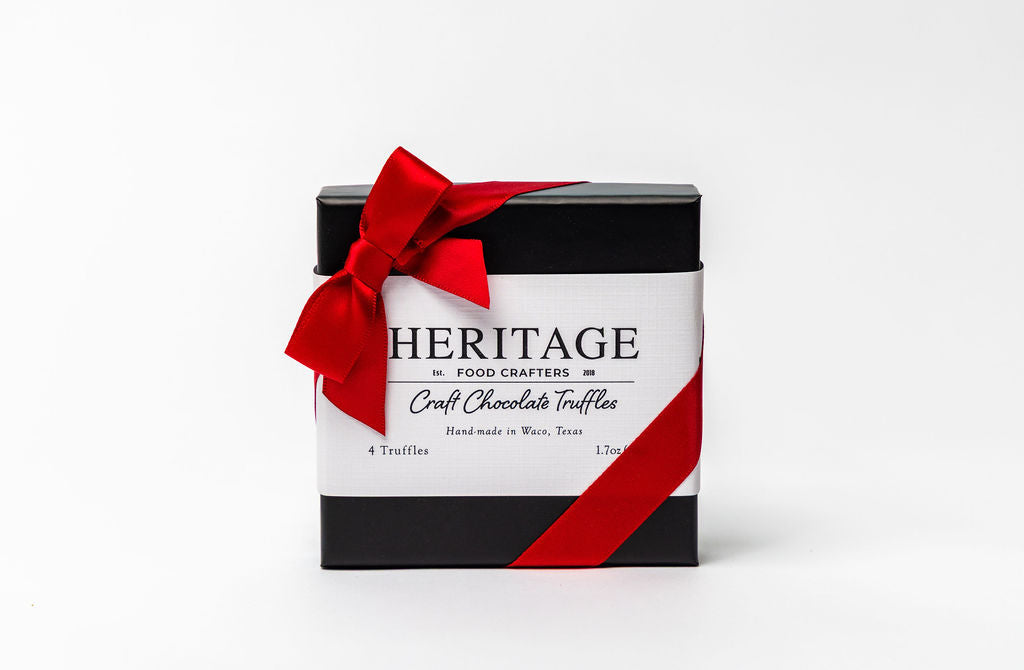 Box of Heritage chocolate truffles with a red ribbon on a white background