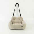 Beige pet seat with a black strap on a white background