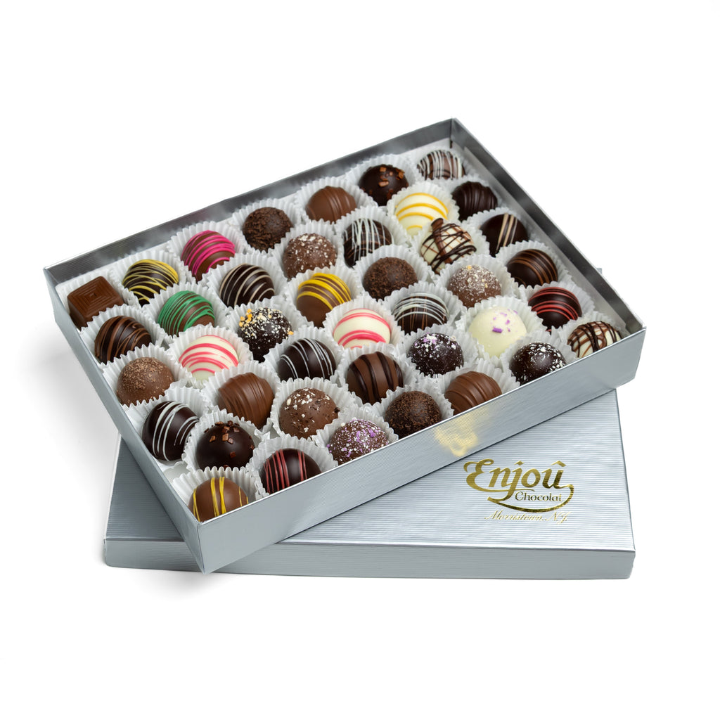 Open gift box of assorted Enjou Chocolat handcrafted truffles with the box lid resting underneath