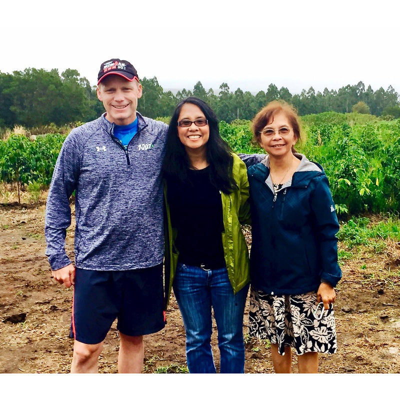 Three people standing together in a field with trees in the background