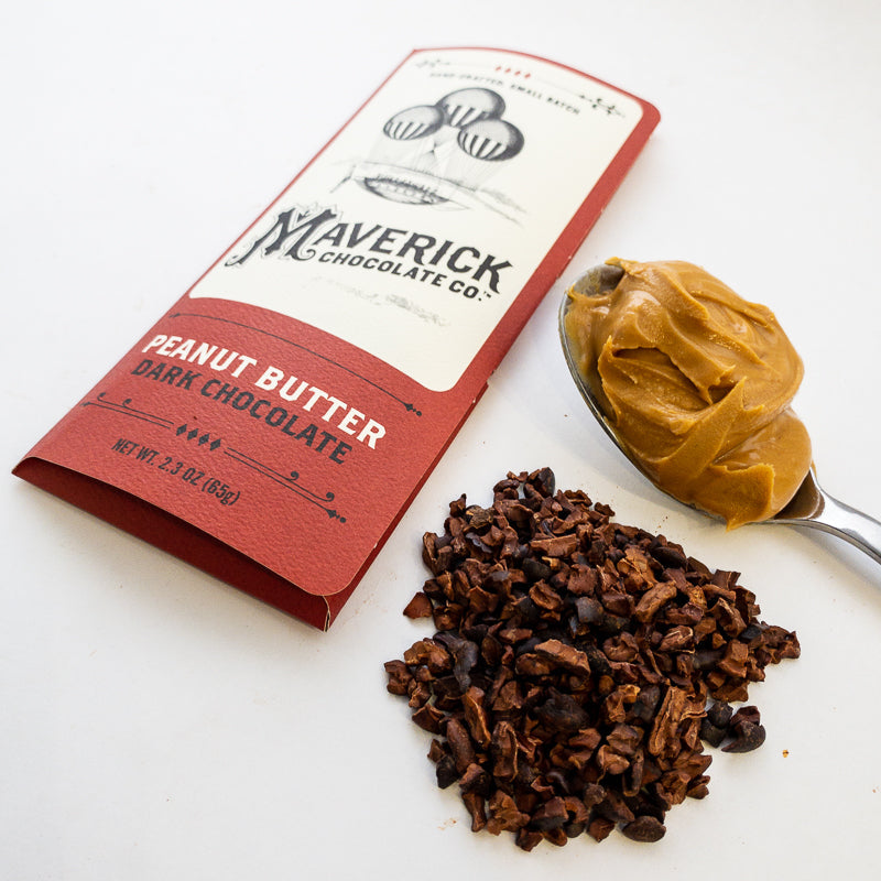 Maverick Chocolate Co. peanut butter dark chocolate bar with a spoonful of peanut butter and chocolate pieces on a white background.
