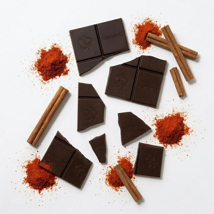 Spicy Cayenne & Cinnamon dark chocolate bar ingredients with cinnamon sticks and red spice powder by Elements Truffles